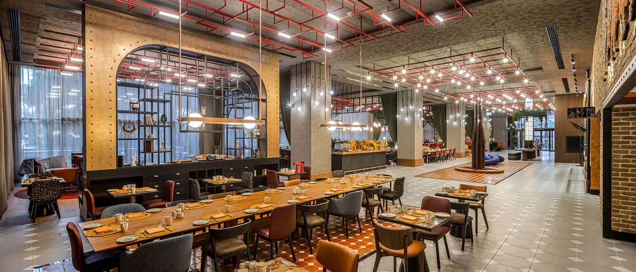 Canopy by Hilton — Restoran: uzun masalar ve kırmızı tavan tesisatı