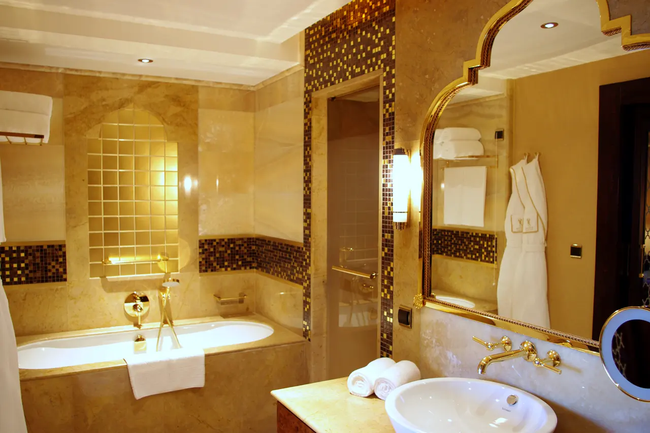 Mardan Palace — Banyo: altın çerçeveli ayna, mozaik şerit ve küvet