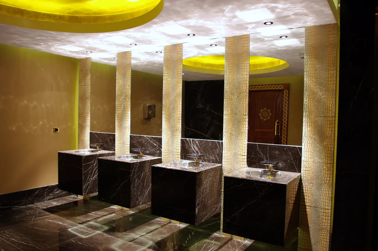 Mardan Palace — Işıklı sütunlar arasında siyah lavabo blokları