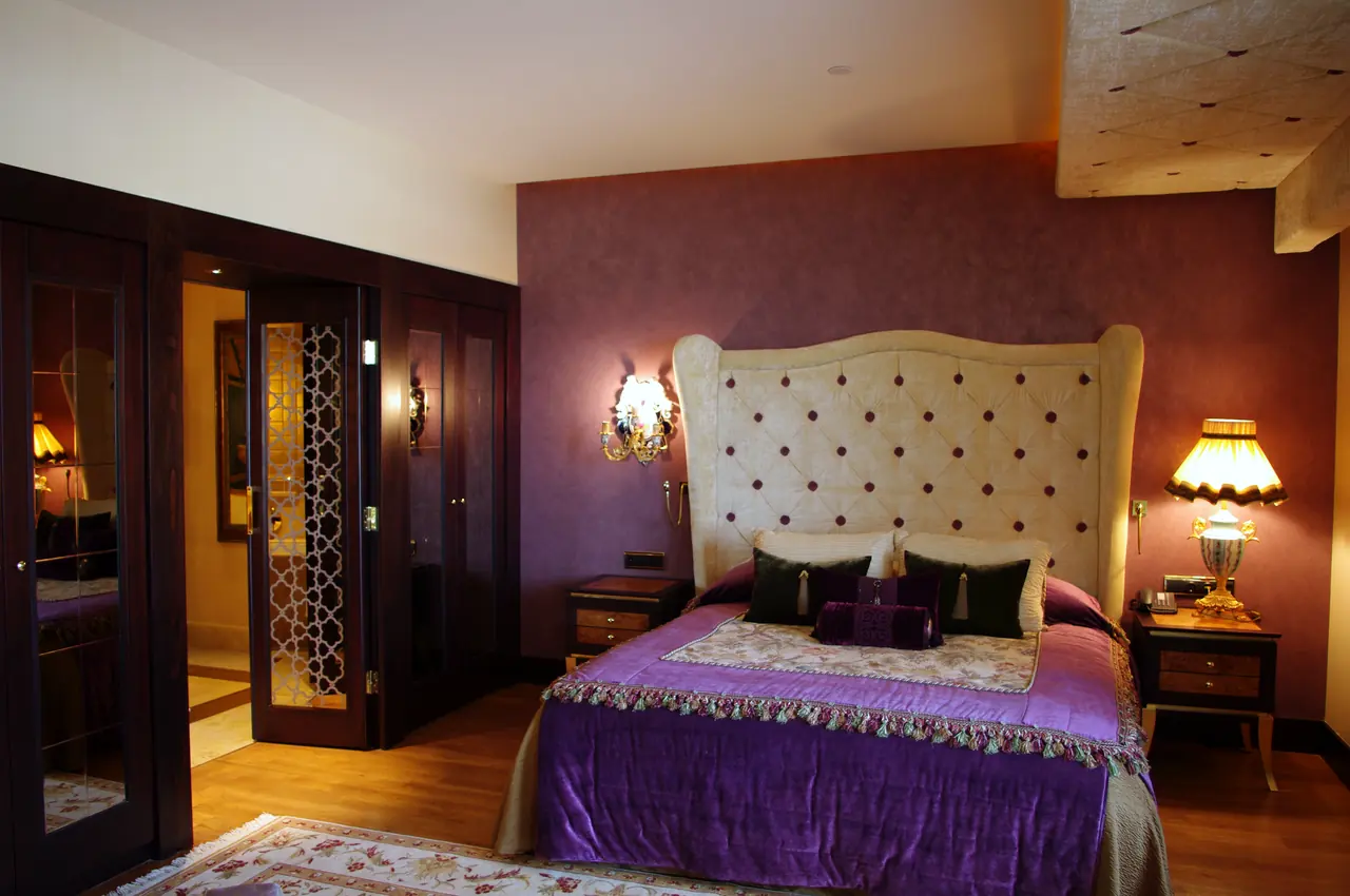 Mardan Palace — Yatak odası: kapitoneli yatak başı, mor örtü