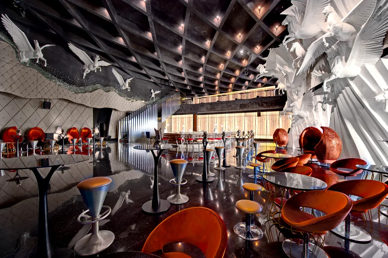 Maxx Royal Belek — Bar: kuş heykelleri, turuncu koltuklar ve yüksek masalar