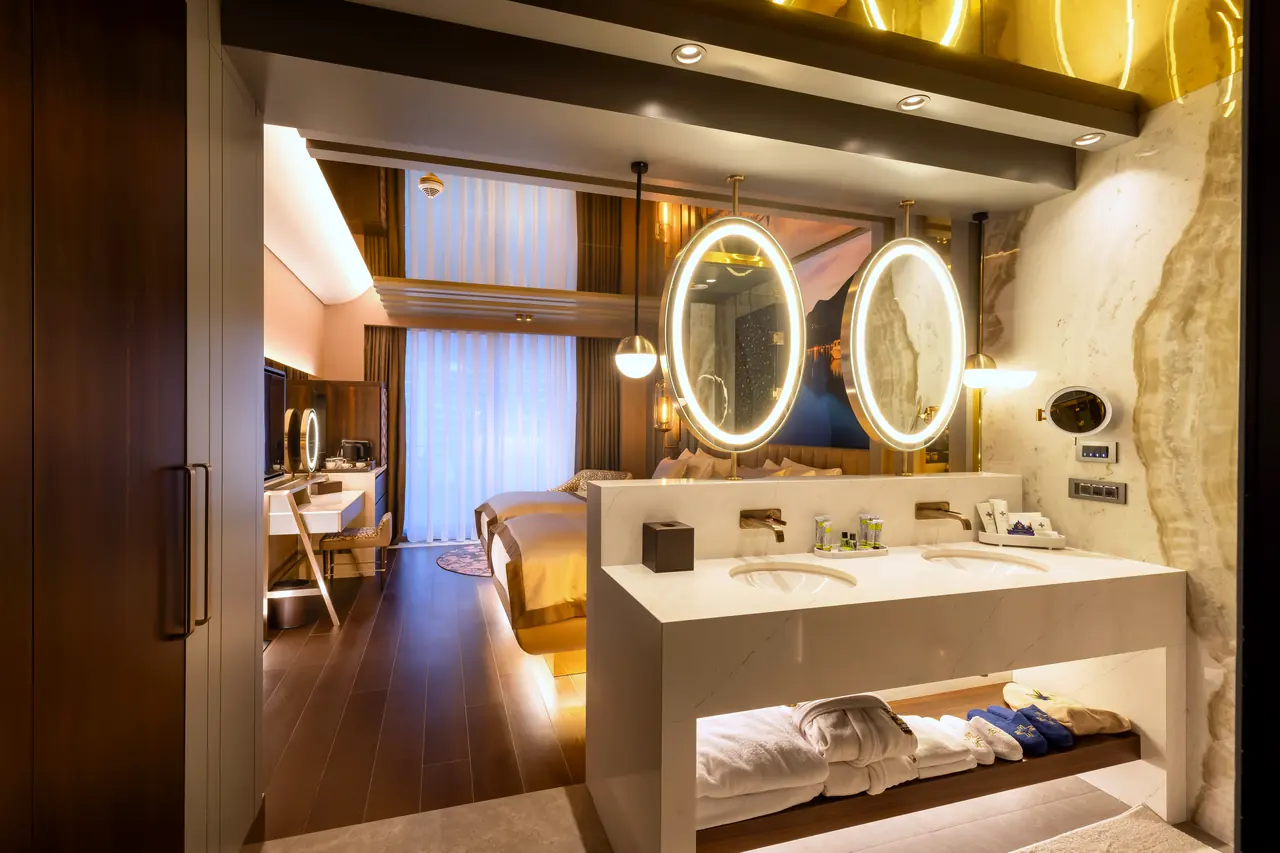Merit Starlit Hotel Residence — Işıklı oval aynalı lavabo ve yatak alanı