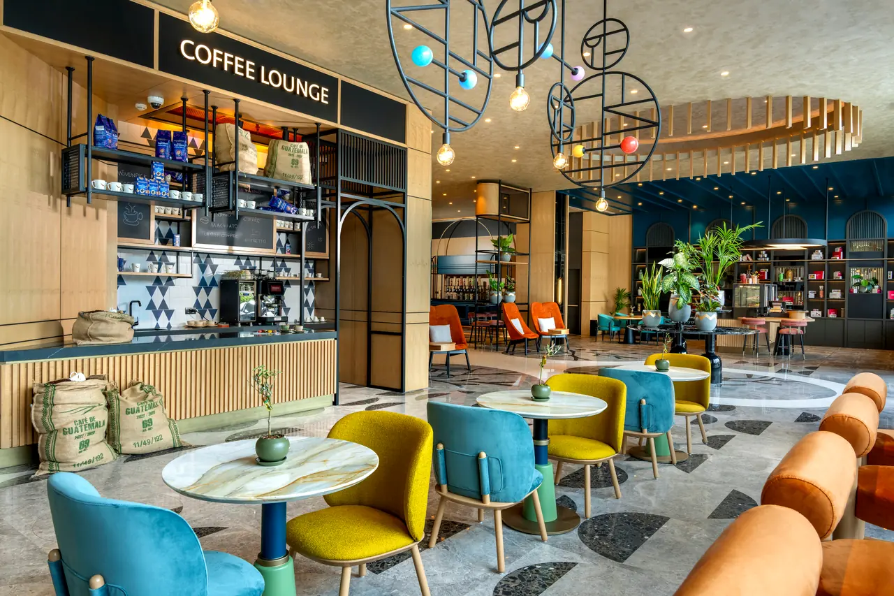 Mövenpick Marmara Sea — Coffee Lounge: raflı kahve bankosu ve renkli koltuklar