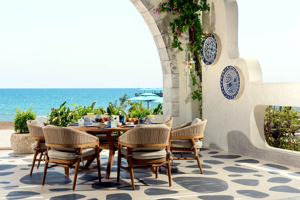 Regnum The Crown · Restoran — Deniz kıyısında beyaz duvarlı terasta masa