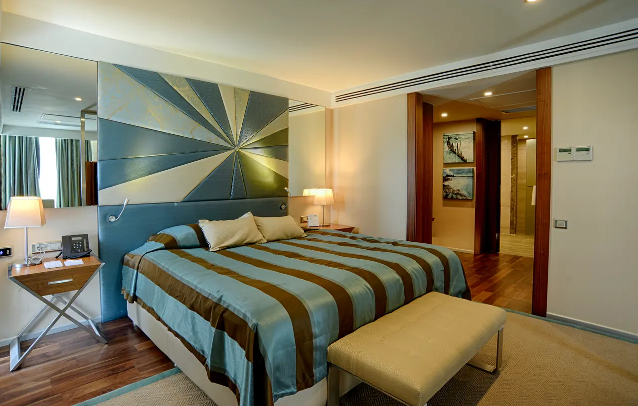 Rixos Premium Belek — Yatak odası: ışınsal desenli yatak başı, çizgili örtü