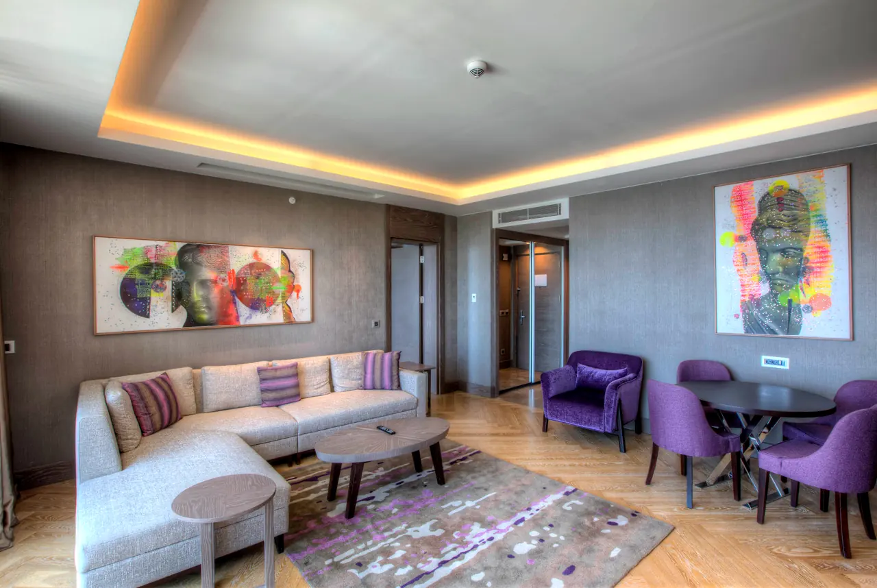 Sirene Luxury Hotel — Süit salonu: L kanepe ve mor koltuklar