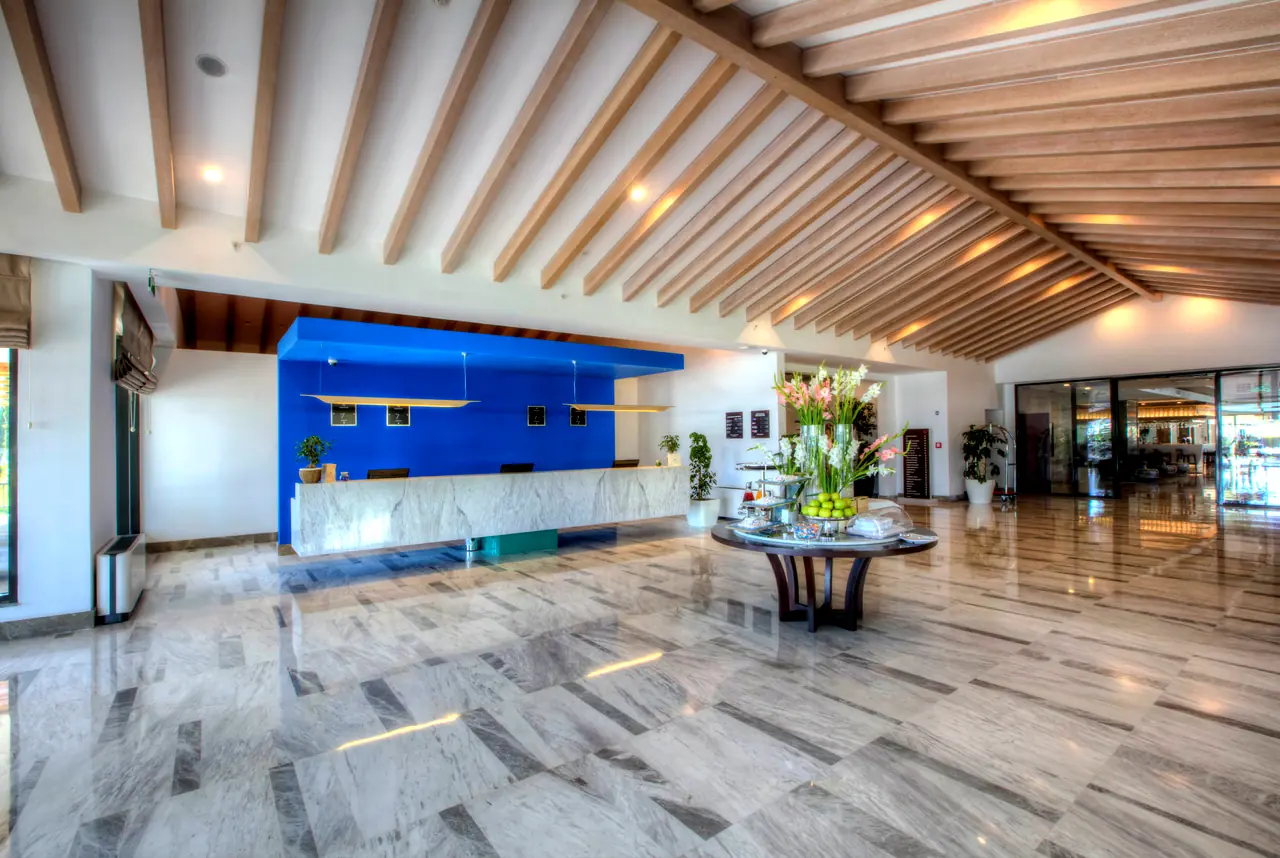 TUI Sensatori Barut — Lobi: mavi duvarlı resepsiyon ve ahşap kirişli tavan