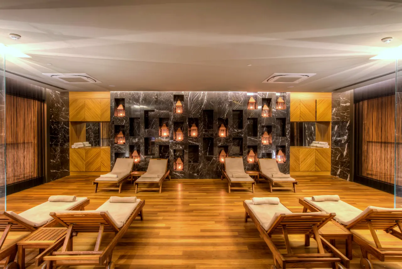 TUI Sensatori Barut — Spa dinlenme alanı: ahşap şezlonglar ve nişli duvar