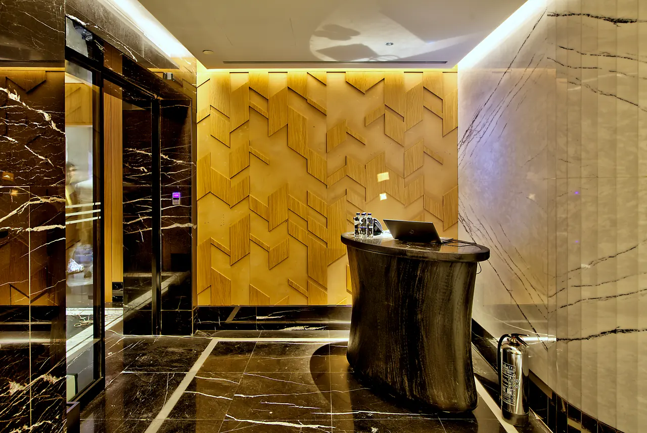 Vakko Hotel — Geometrik ahşap duvar ve koyu mermer zeminli giriş