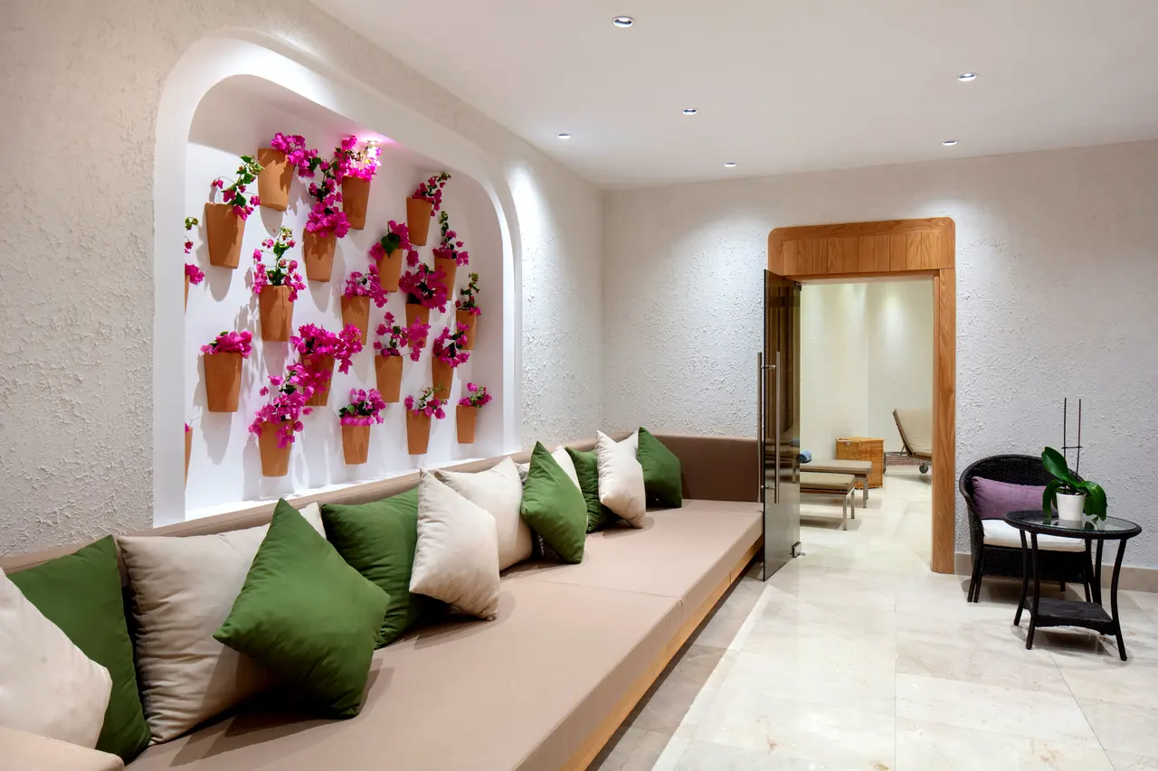 Xanthe Resort & Spa — Spa bekleme: çiçekli saksı duvarı ve minderli sedir